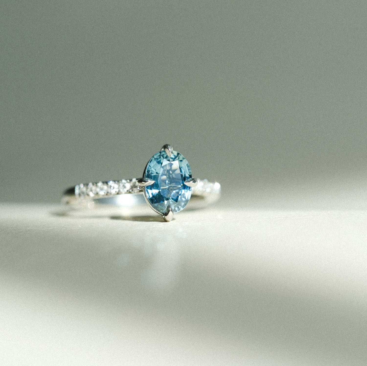 MILA Platinum Solitaire Ring with Oval Teal Sapphire and Diamond Shoulders made in recycled platinum by ethical jeweller E.C.One London in our B Corp certified workshop