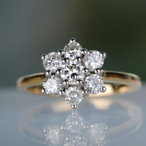 Diamond ring with a star-shaped design on a reflective surface with a blurred background