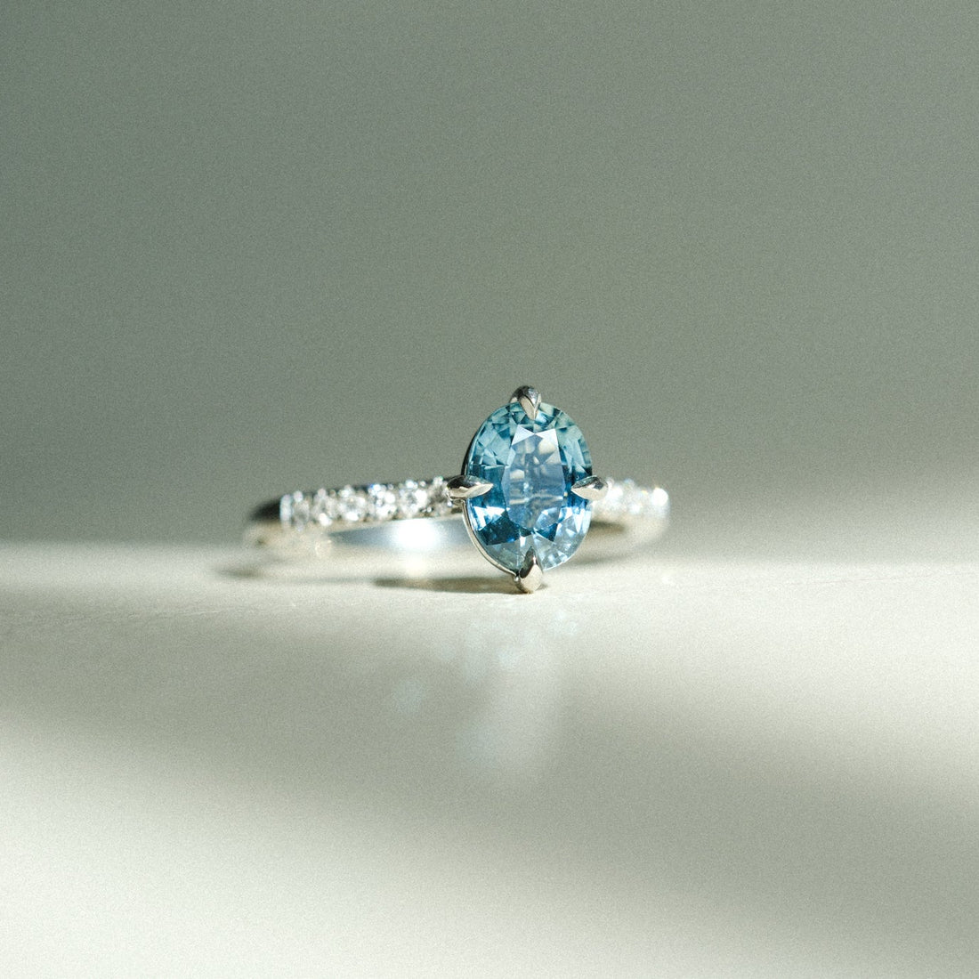 MILA Platinum Solitaire Ring with Oval Teal Sapphire and Diamond Shoulders