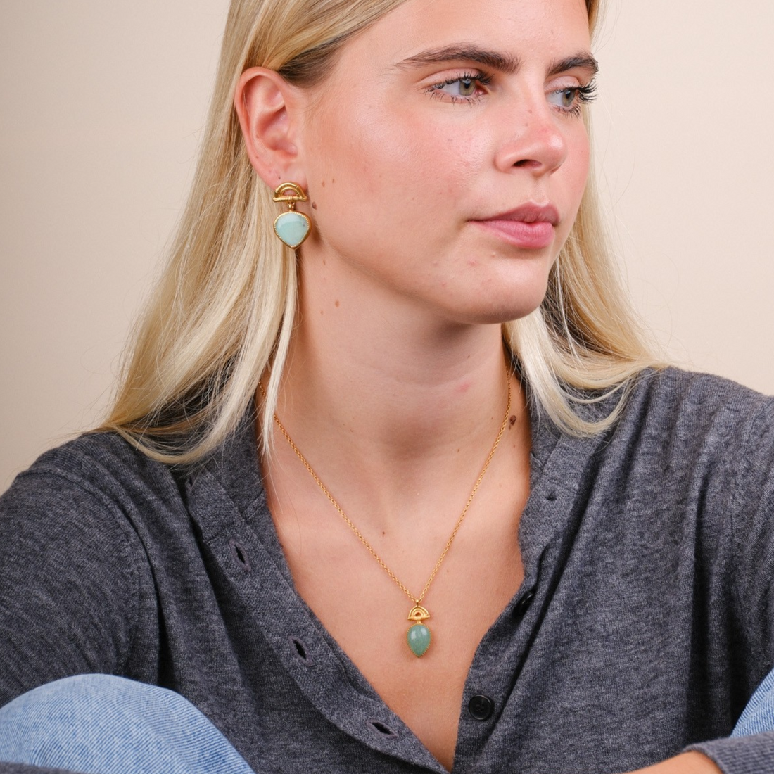 EC One model wearing a gold plated bamboo arch pendant with a pear-shaped green Aventurine gemstone on a fine chain.