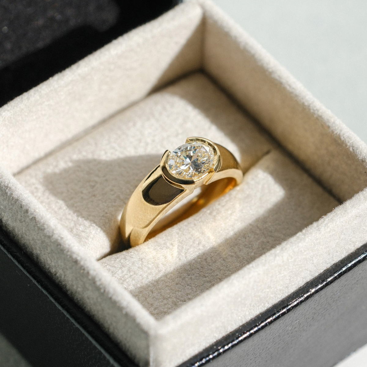 EC One EDIE engagement ring in 18ct yellow gold with a chunky band and a demi-rub over set oval white diamond.
