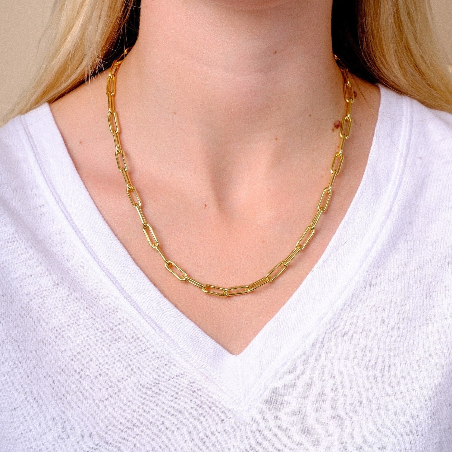 EC One gold plated recycled silver paperclip chain necklace worn on a model in a white v-neck t-shirt.