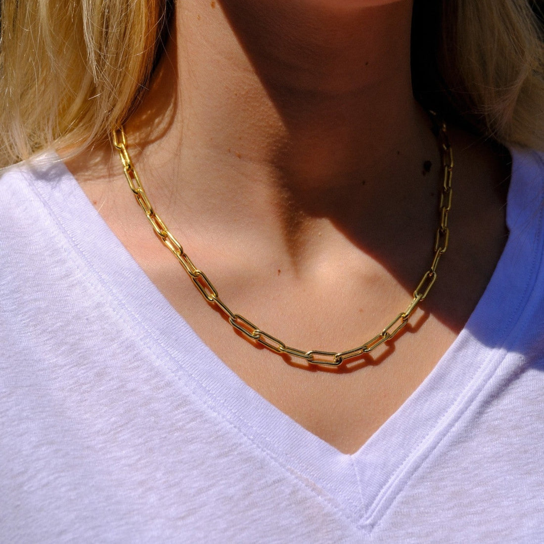 EC One heavy gold plated recycled silver paperclip chain necklace worn by a woman in a white v-neck shirt