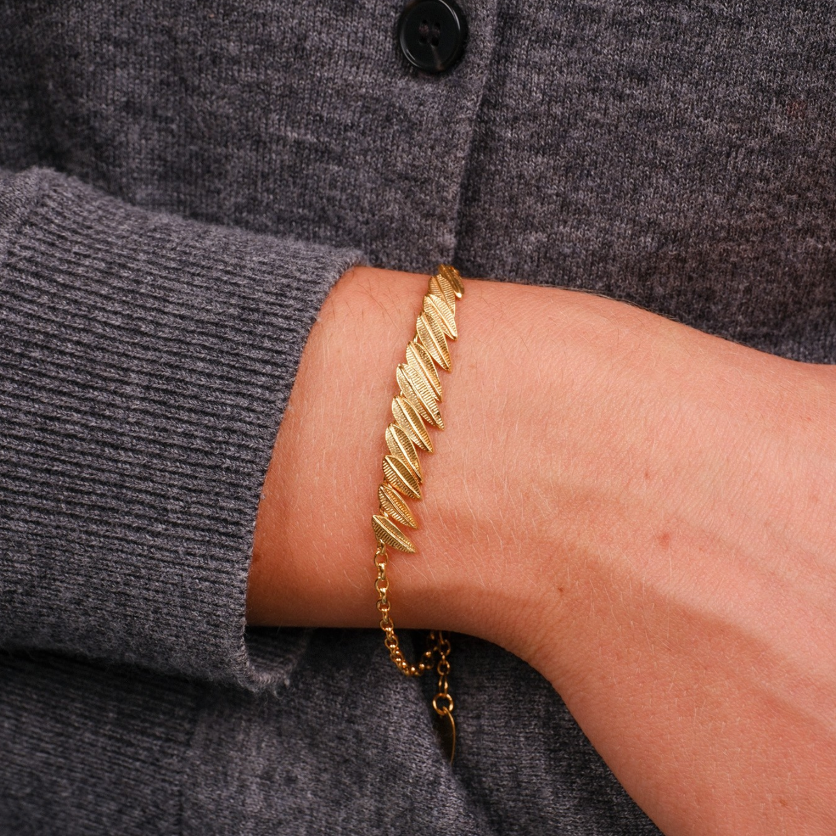 EC One gold plated Phoenix Plume bracelet featuring a textured feather design on a delicate chain worn on a wrist