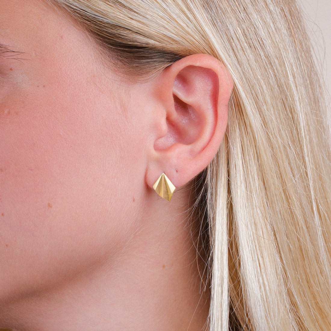 EC One gold plated recycled silver pleated stud earrings worn on a model, featuring an angular art deco design.