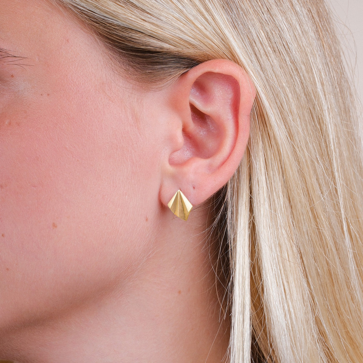 EC One gold plated recycled silver pleated stud earrings worn on a model, featuring an angular art deco design.