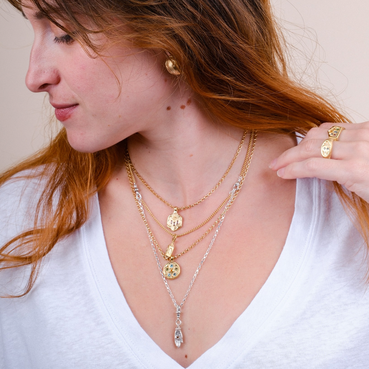 EC One layered silver and gold plated chain necklace with small lantern charm worn by a woman in a white t-shirt
