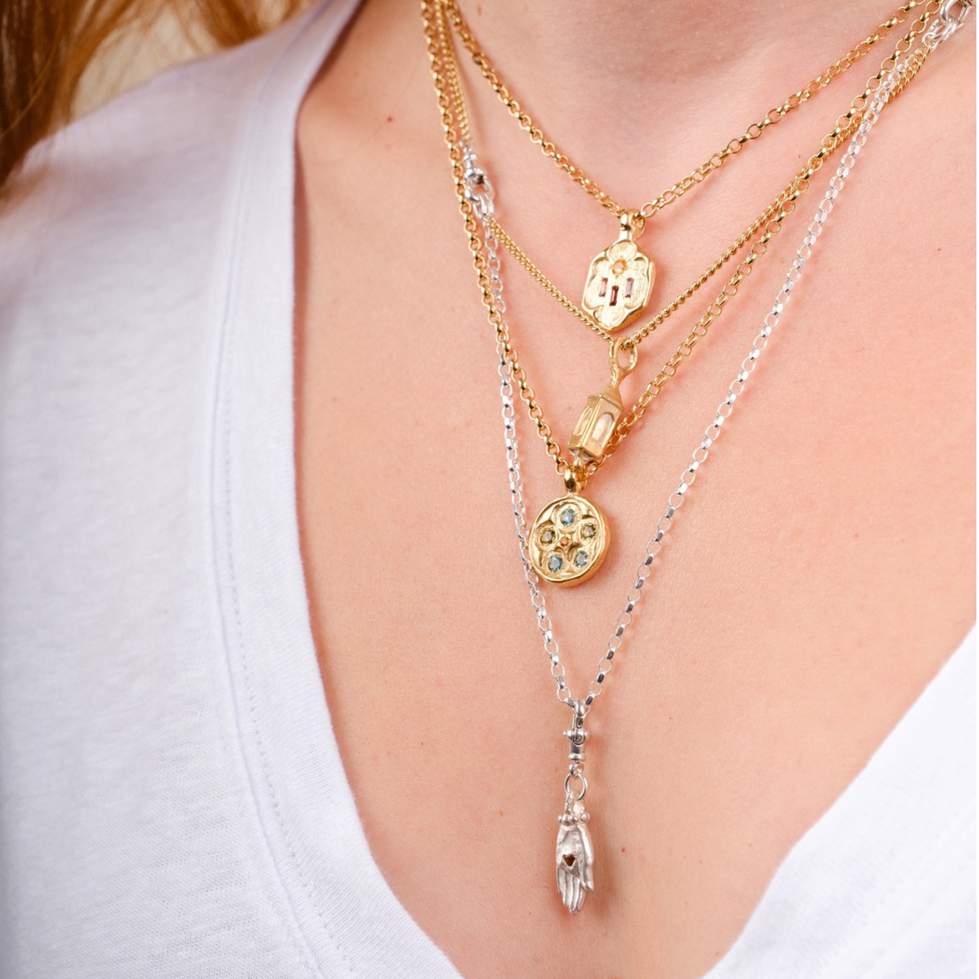 EC One layered pendant necklaces featuring gold plated rose window and silver charms on a model wearing a white top.