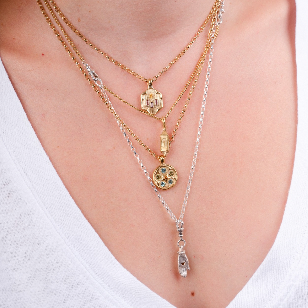 EC One layered necklace featuring mixed silver and gold plated chains with small lantern and hand charms on a model