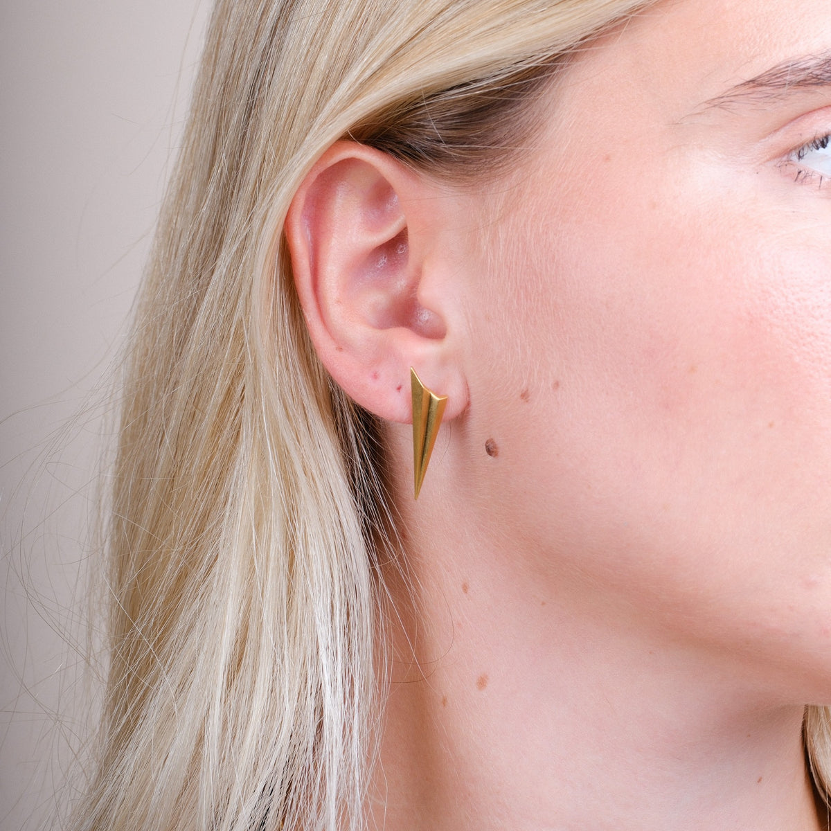EC One long pleated gold plated recycled silver stud earrings worn on a model, featuring an angular spiked design.