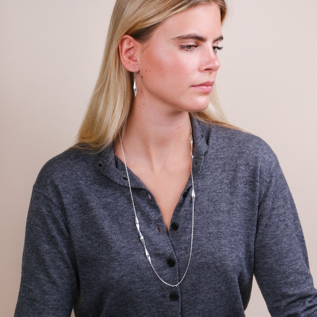 EC One long silver shard necklace worn by a woman, featuring multi-faceted hand-carved recycled silver pendants.