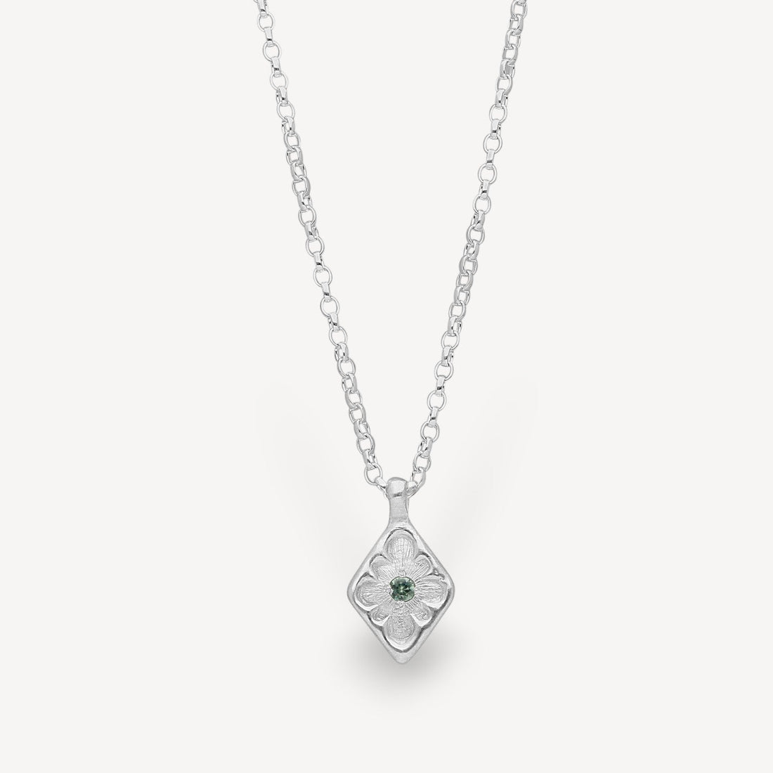 EC One lozenge-shaped silver pendant necklace featuring an intricate floral engraving and a central green sapphire.