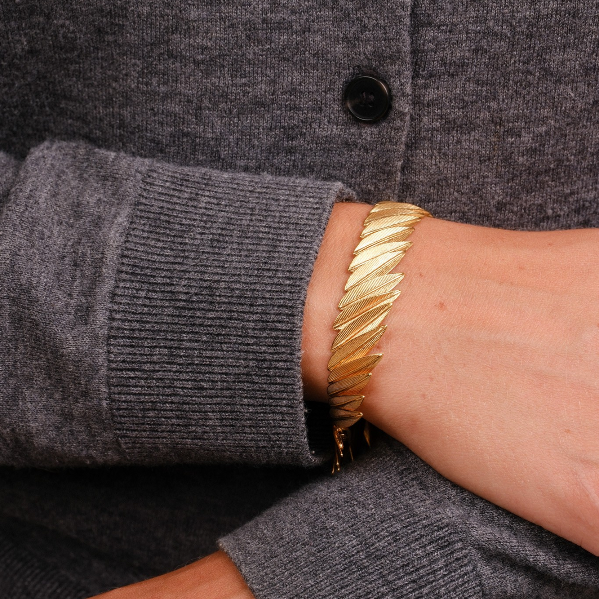 EC One PHOENIX gold plated recycled silver contour bracelet with a fluid, textured feather-like design on a wrist.