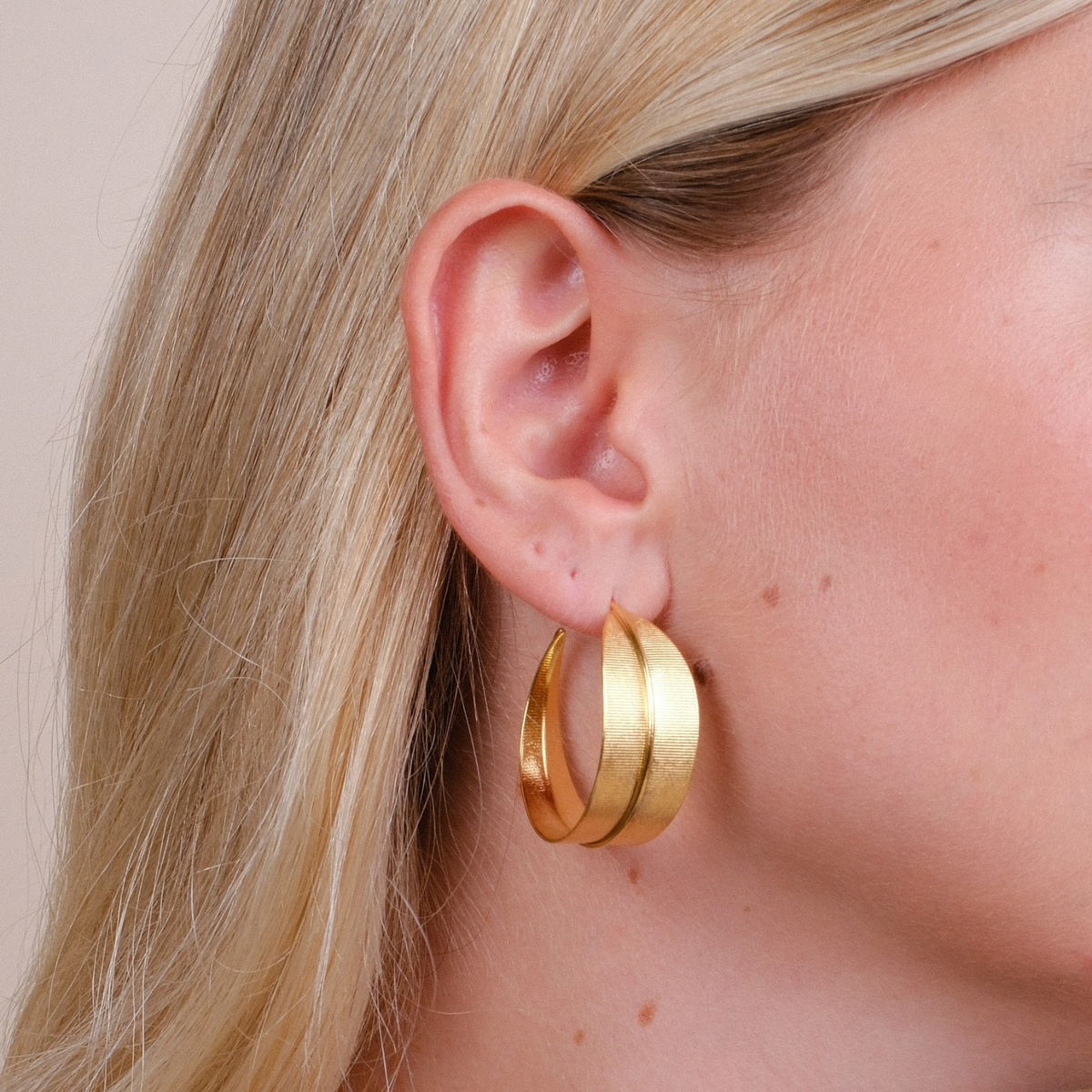 EC One Phoenix large gold plated hoop earrings with a textured finish worn on a model