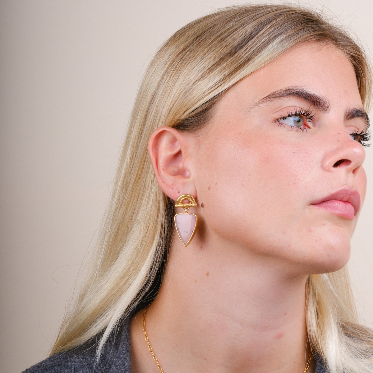 EC One Rosita Bonita gold plated bamboo arch stud earrings with pear-shaped pink opal worn by a blonde model