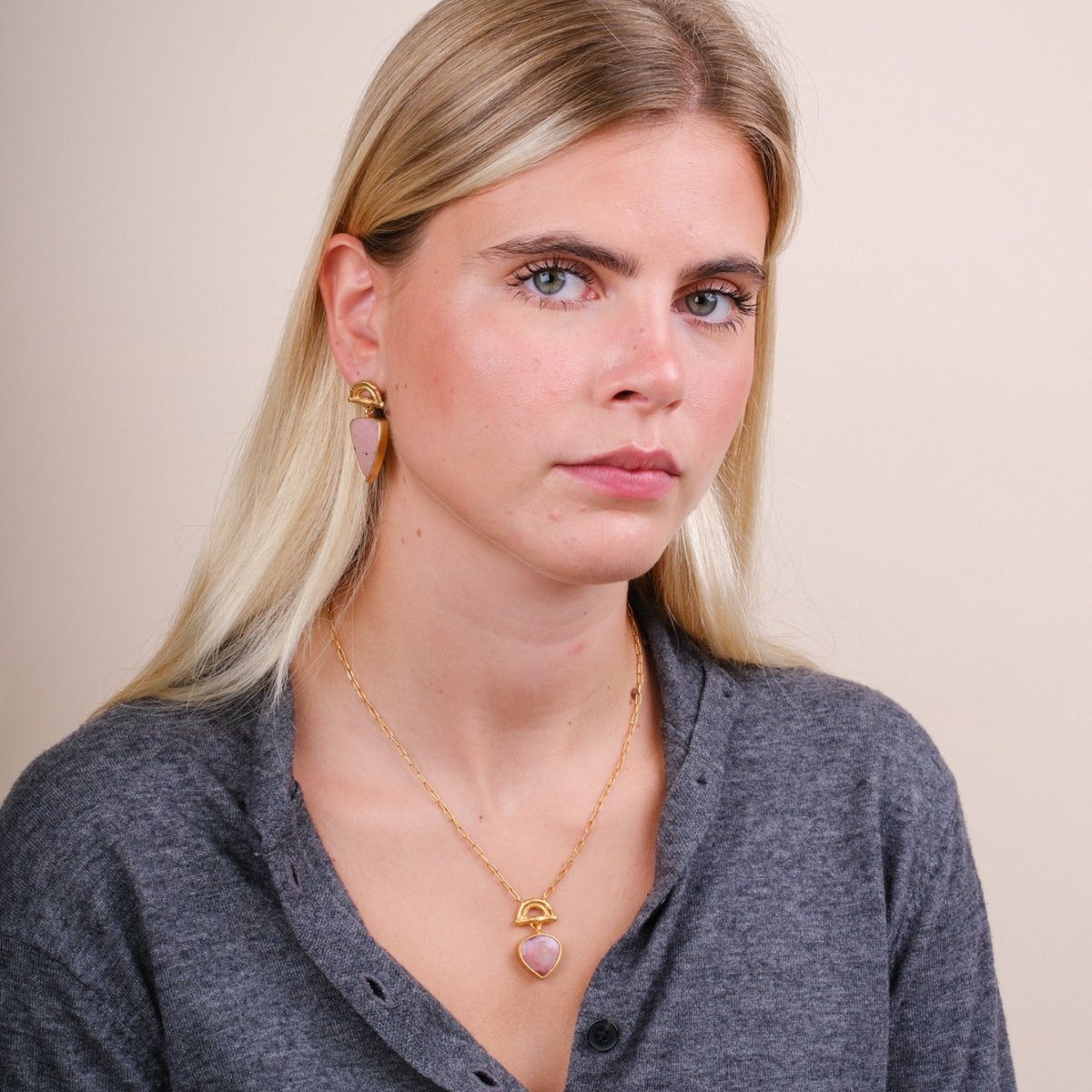 EC One model wearing a gold plated bamboo sunrise pendant with a pear-shaped pink opal gemstone on a delicate chain