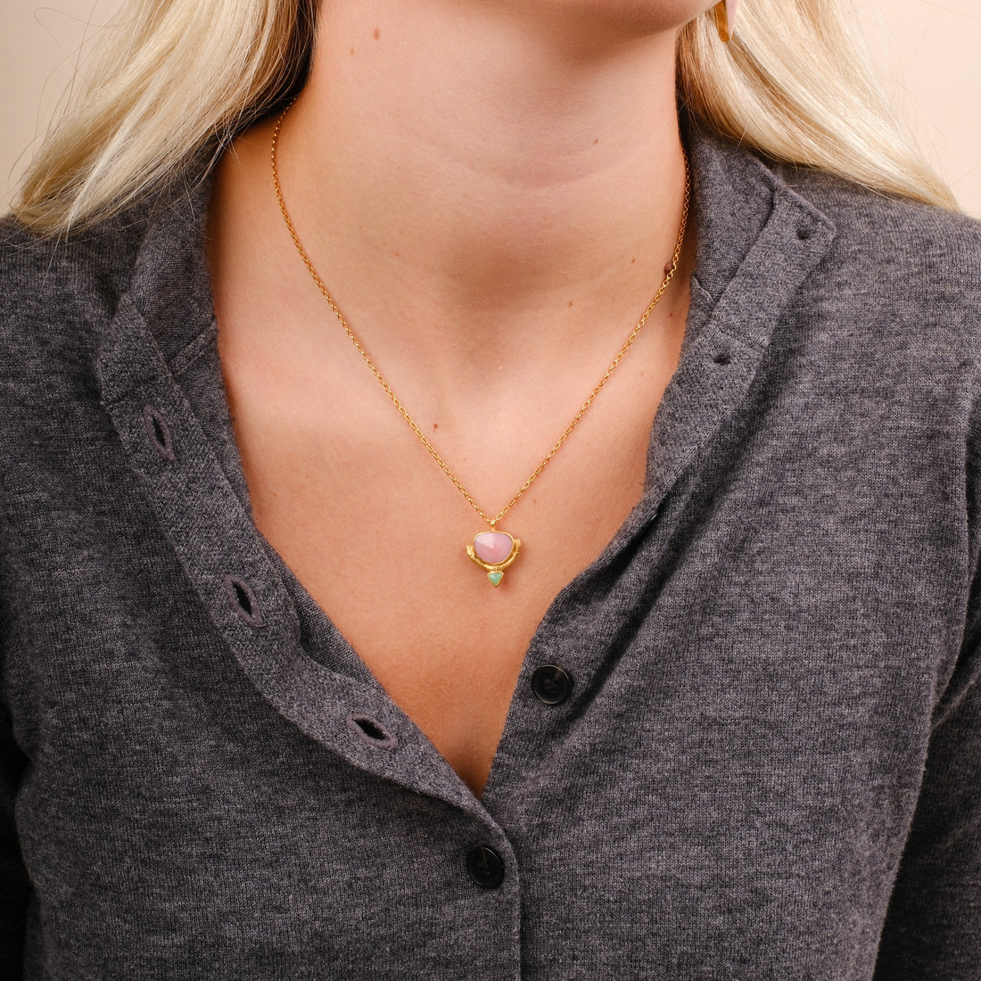 EC One Rosita Bonita gold plated necklace featuring a pink opal and chrysoprase pendant on a model wearing grey.
