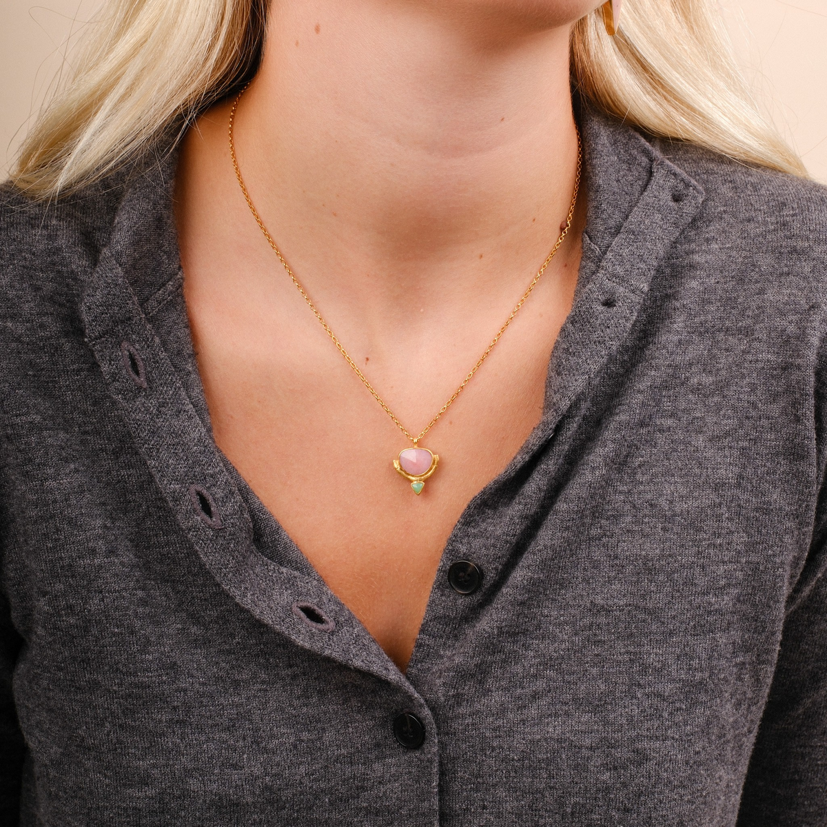 EC One Rosita Bonita gold plated necklace featuring a pink opal and chrysoprase pendant on a model wearing grey.