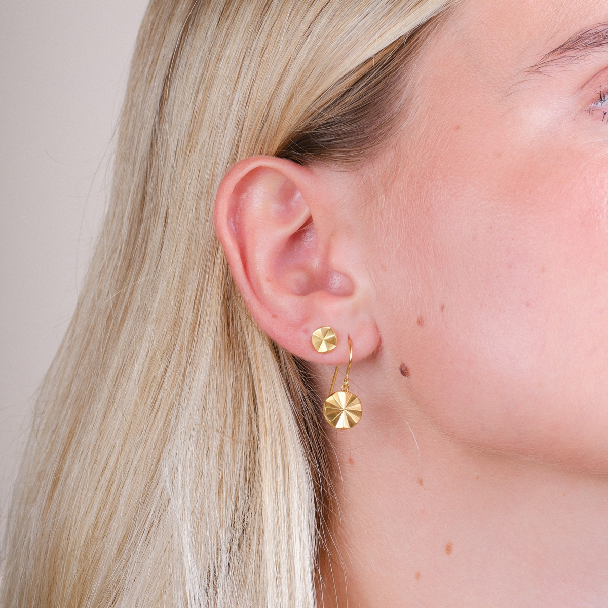 EC One Polaris Starburst gold plated recycled silver drop hook earrings worn on a model's ear
