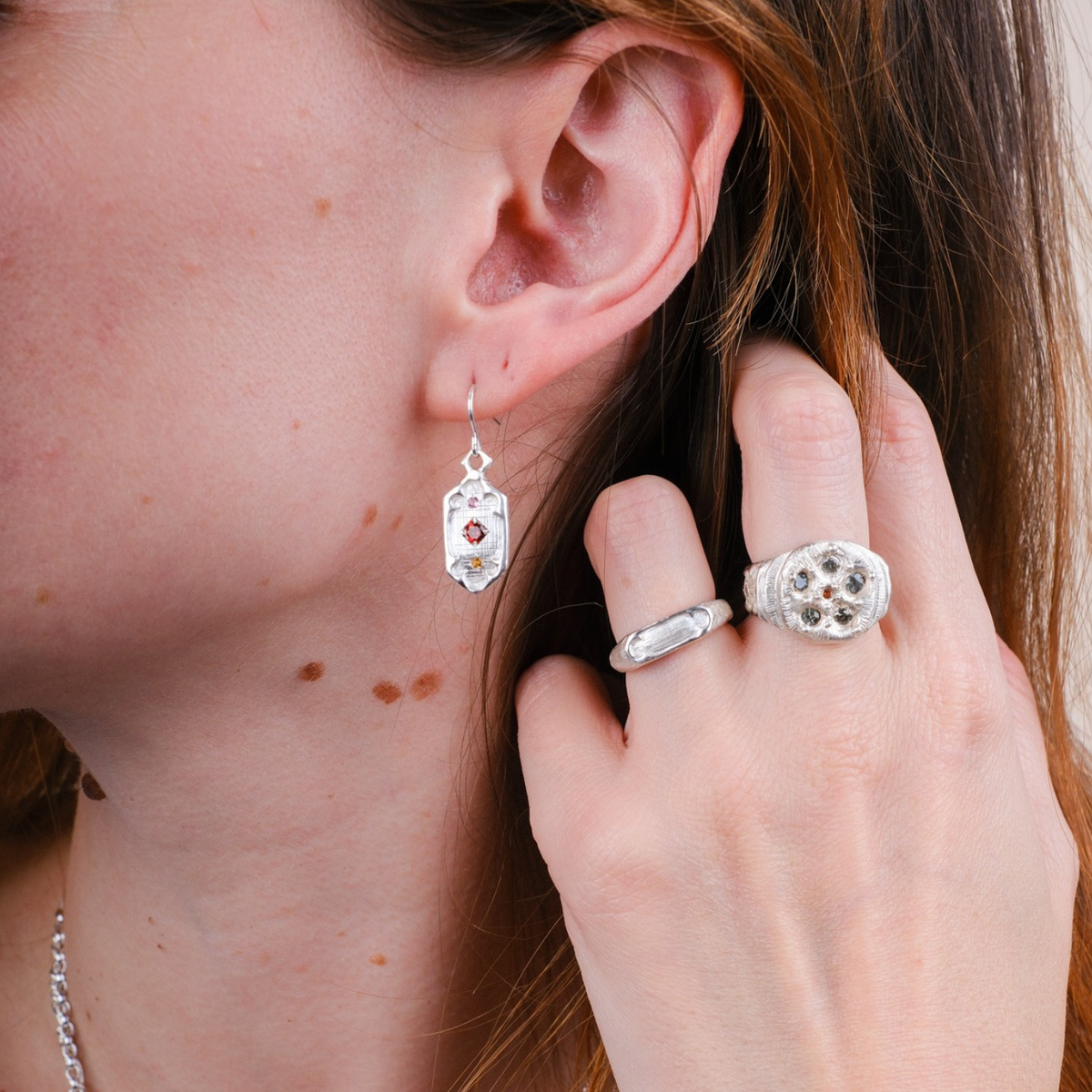 EC One Rose Window silver ring with sapphire detail worn on a hand alongside a matching silver earring