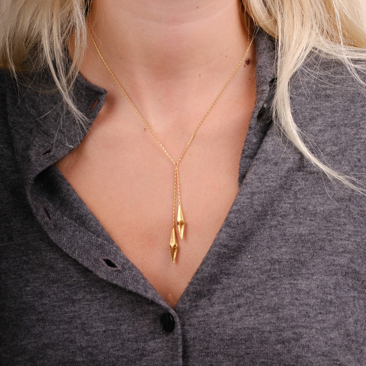 EC One Shard double drop necklace in gold plated recycled silver worn on a model against a grey top