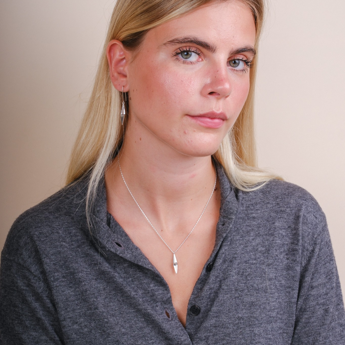 EC One Shard single drop necklace in recycled silver worn by a blonde woman with matching drop earrings