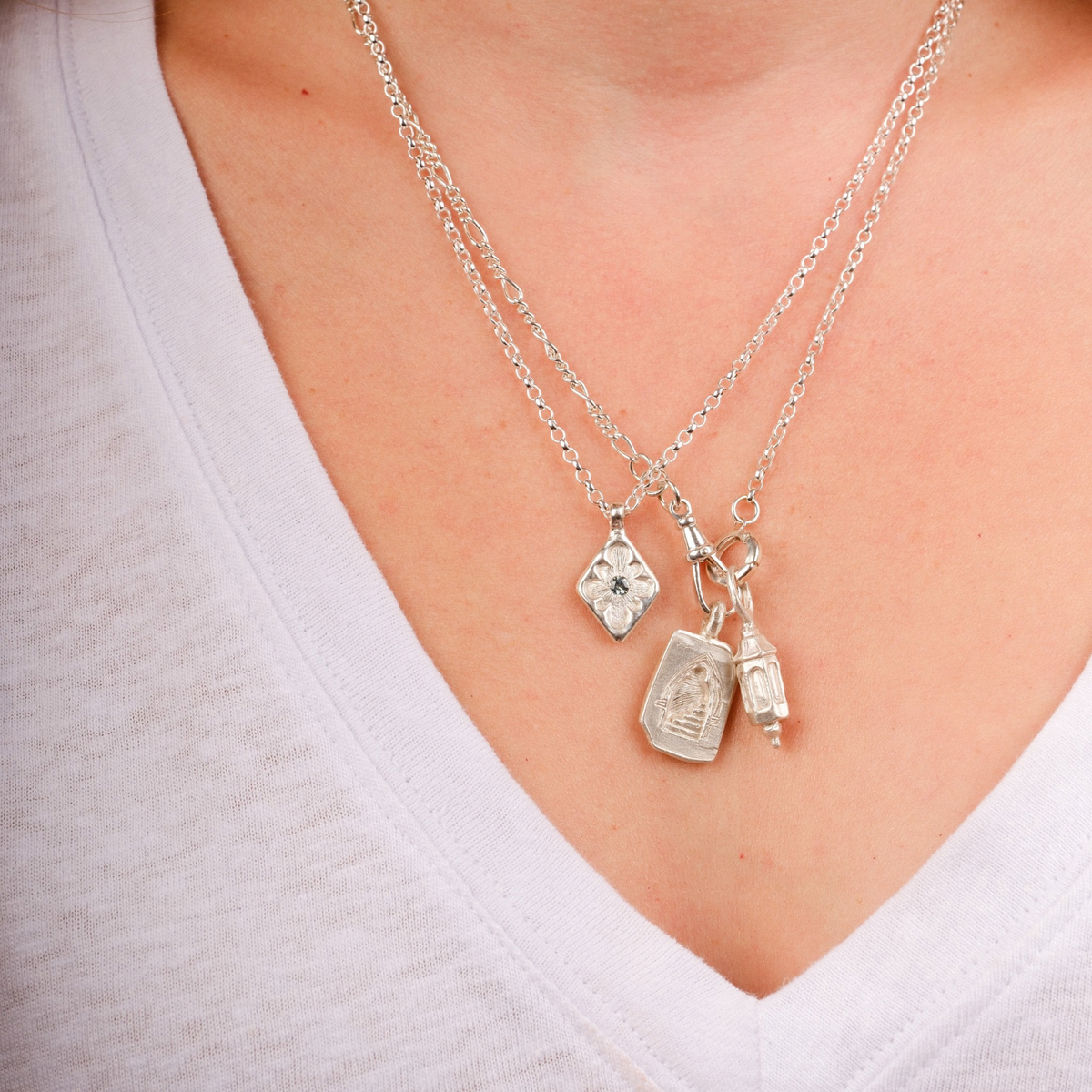 EC One silver lantern charm necklace worn on a model with a delicate chain and additional small geometric charms