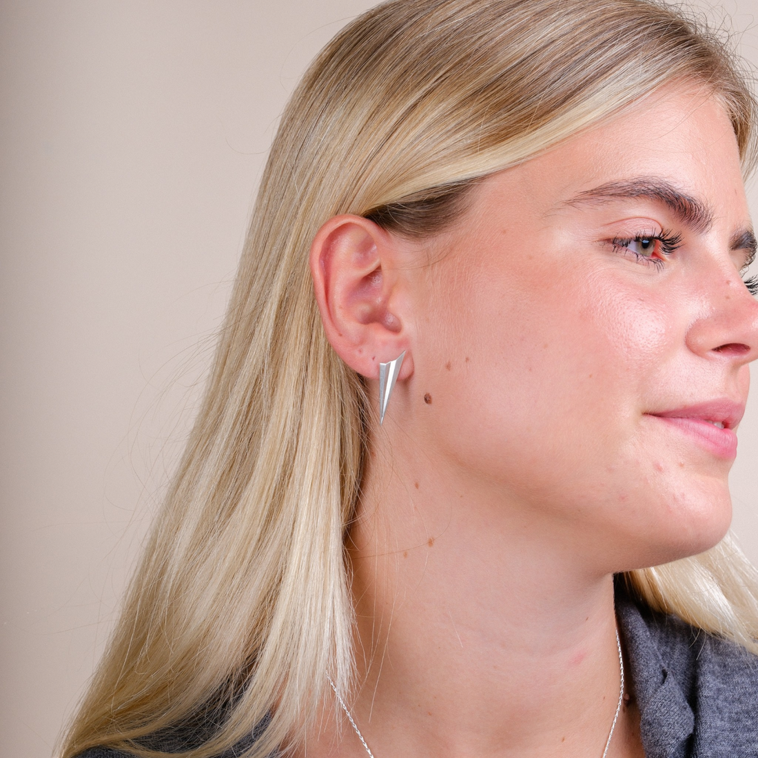 EC One silver long pleated stud earrings with an angular, spiked design worn by a blonde model