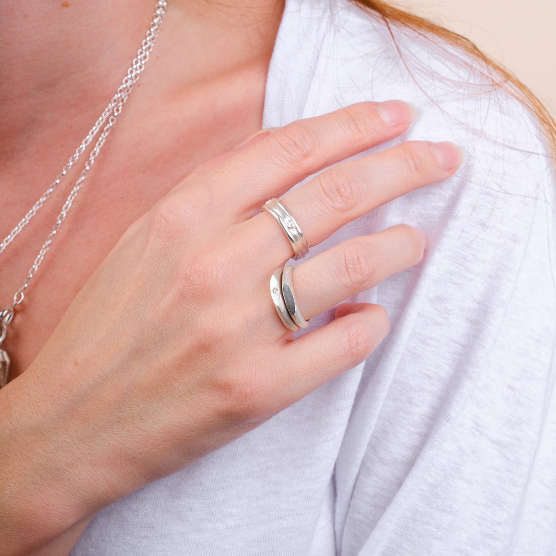 EC One skinny silver signet rings with small brown diamonds worn on a woman's hand against a white top