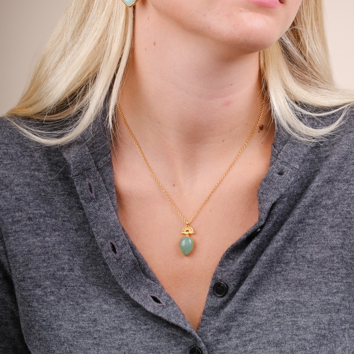 EC One SUNRISE mini pendant featuring a pear-shaped green aventurine stone on a gold-plated chain worn by a model