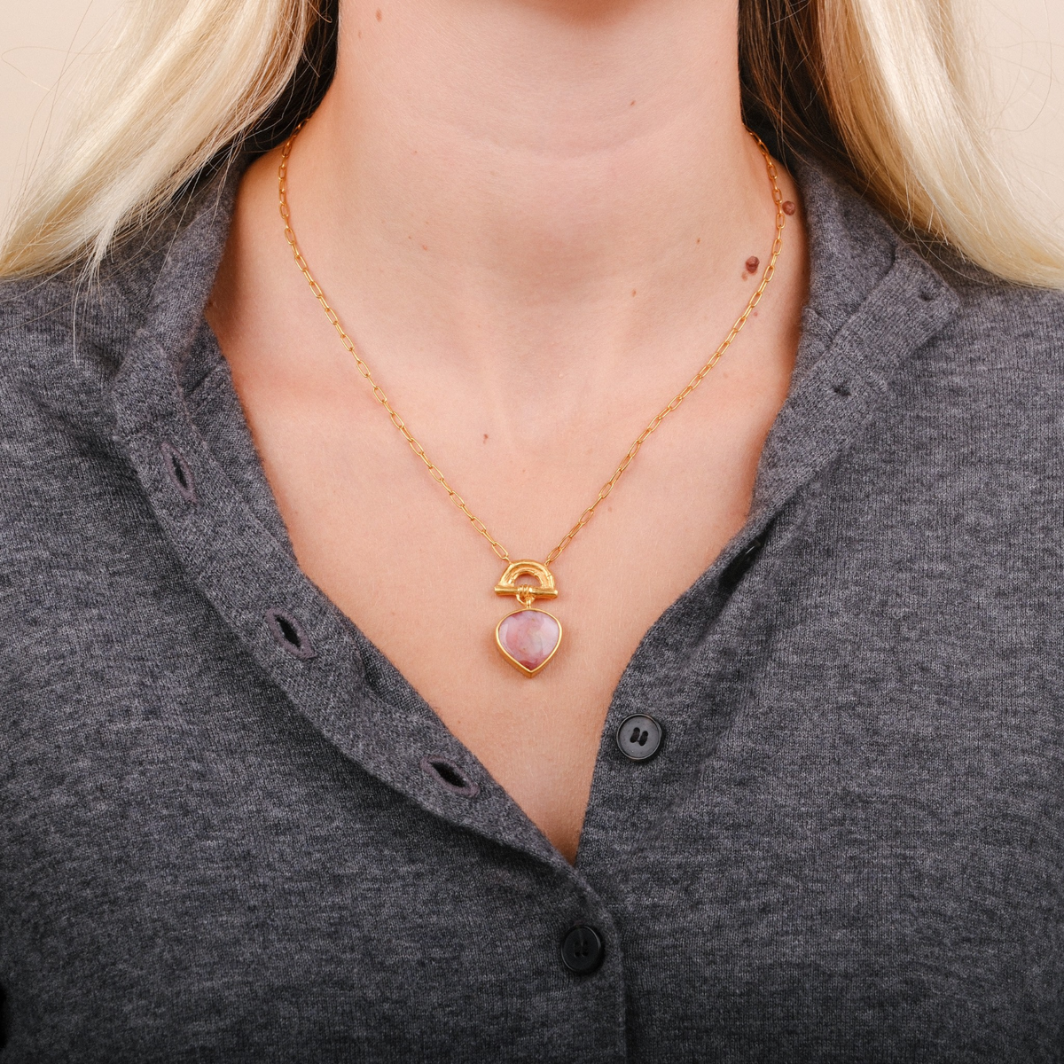 EC One SUNRISE pendant featuring a pear-shaped pink opal gemstone on a gold-plated bamboo arch, worn on a gold chain.