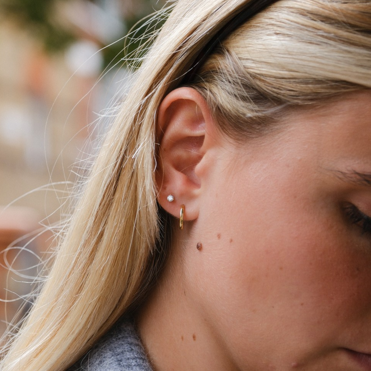 EC One single 18ct yellow gold huggie hoop earring worn on a woman's earlobe for everyday style.